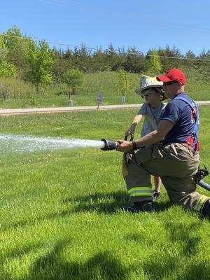 Firefighter and child spraying firehose